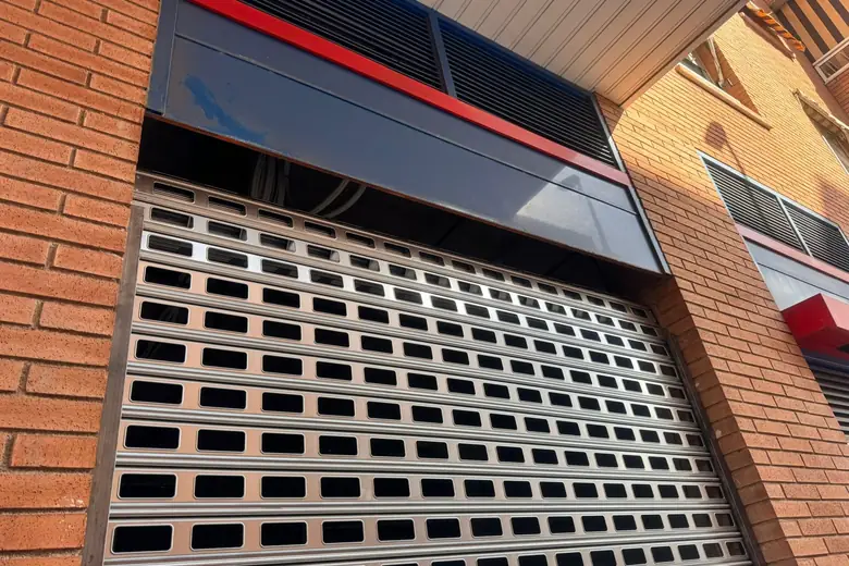 Cierre metálico troquelado nuevo en la fachada de un local, visto desde la calle